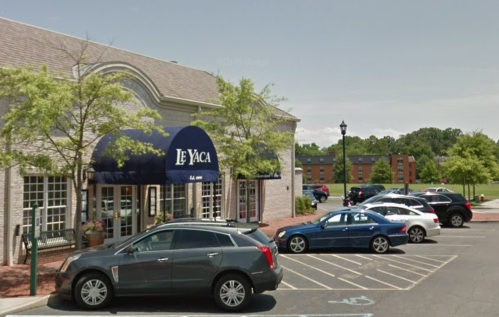 Exterior view of Le Yaca restaurant with parked cars and trees in the foreground.