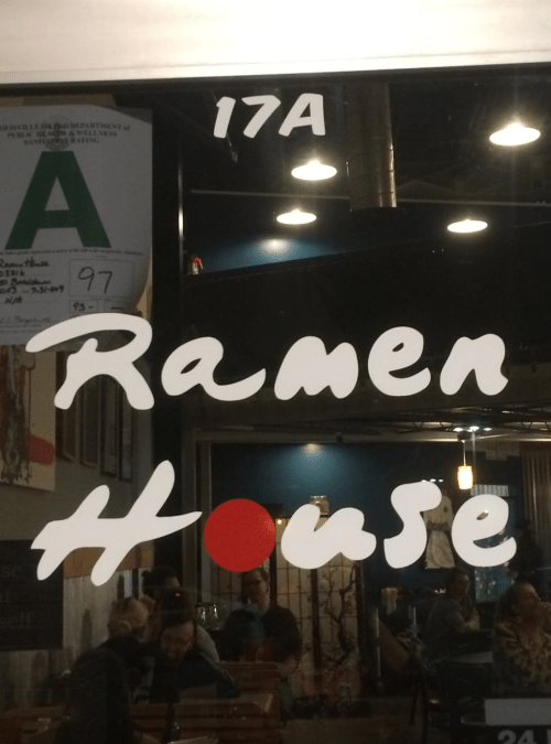 Sign for "Ramen House" with a red circle, visible through a restaurant window.