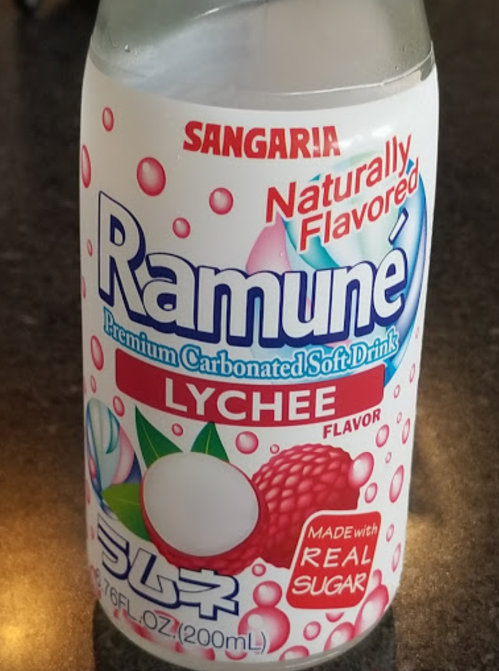 A bottle of Sangaria Ramuné lychee-flavored carbonated soft drink, featuring a colorful label and a clear liquid.