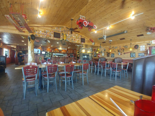 Cozy restaurant interior with wooden decor, empty tables, and vintage memorabilia hanging from the ceiling.