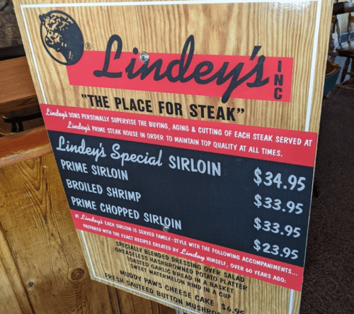 Menu board for Lindey's Inc. featuring steak options and prices, including special sirloin and broiled shrimp.