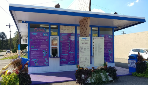 A colorful ice cream shop with a menu displayed outside, featuring a bright blue roof and purple walls.