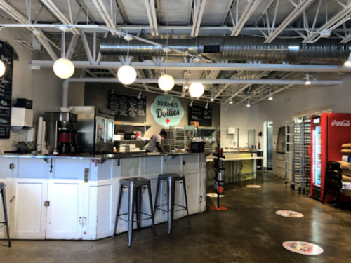A modern donut shop interior with a counter, display cases, and seating, featuring bright lighting and a clean design.
