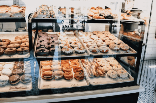 A display case filled with a variety of colorful donuts and pastries, showcasing different flavors and toppings.