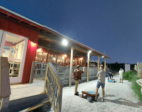 A lively outdoor scene at a restaurant with people playing games and enjoying the evening atmosphere.
