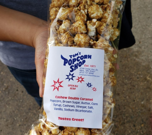 A bag of Cashew Double Caramel popcorn from Tom's Popcorn Shop, featuring a colorful label and a variety of popcorn.