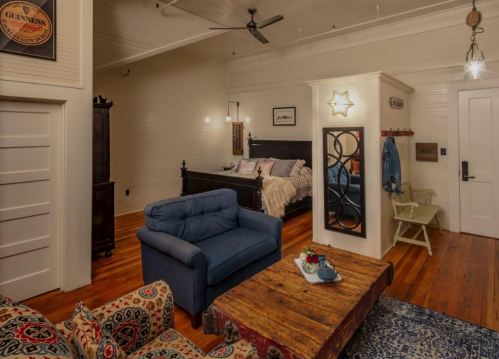 Cozy room featuring a blue sofa, wooden coffee table, and a bed with decorative pillows, set in warm, inviting tones.
