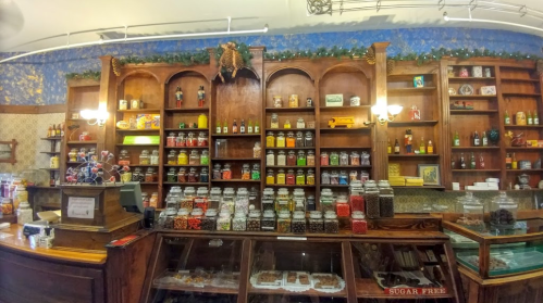 A vintage candy shop interior with wooden shelves filled with jars of colorful candies and treats.