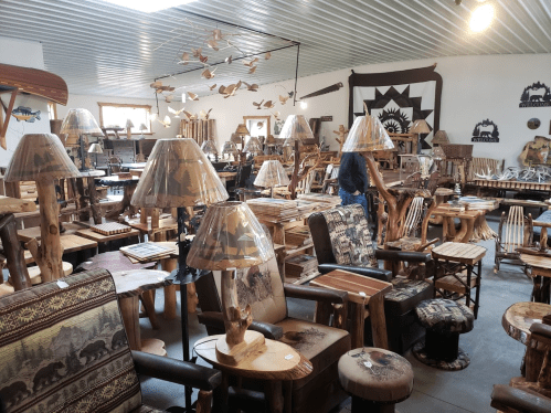 A spacious shop filled with rustic wooden furniture, lamps, and decorative items, showcasing a cozy, artistic atmosphere.