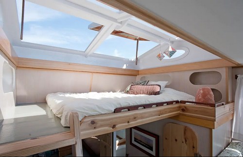 Cozy loft bedroom with a skylight, wooden accents, and soft bedding, creating a bright and inviting space.