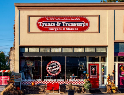 A storefront with a sign reading "Treats & Treasures" featuring burgers, shakes, and a vintage soda fountain theme.