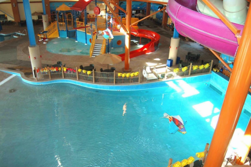 Indoor water park featuring a large pool, water slides, and play areas with colorful structures and seating.