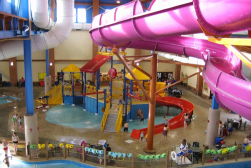 Indoor water park featuring colorful slides, a play area, and a pool with families enjoying the attractions.