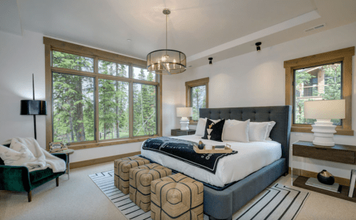 Modern bedroom with large windows, a king bed, stylish decor, and a cozy seating area.