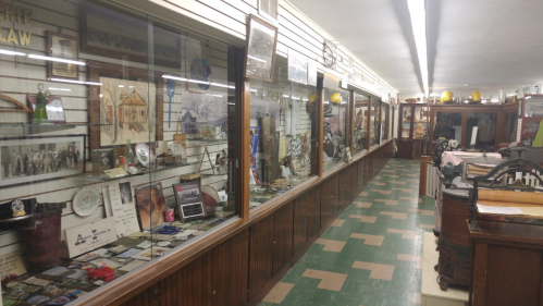 A long display case in a museum showcasing various historical artifacts and memorabilia along a tiled floor.