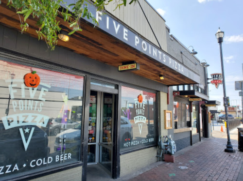 Exterior of Five Points Pizza, featuring a sign and windows with Halloween decorations, on a sunny day.