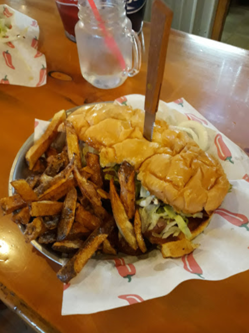A plate with two burgers topped with lettuce and a knife, accompanied by a generous serving of crispy fries.
