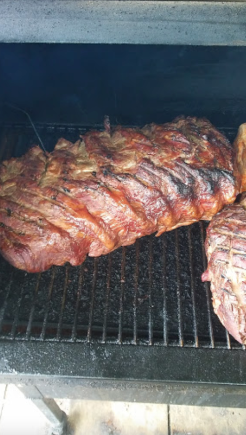 A close-up of smoked meat on a grill, showcasing a rich, caramelized exterior and grill marks.