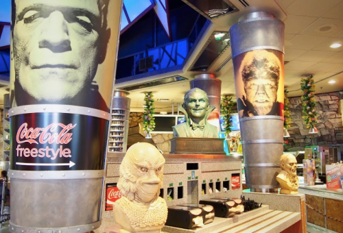 Decorative columns featuring monster faces in a vibrant restaurant with a Coca-Cola Freestyle machine.