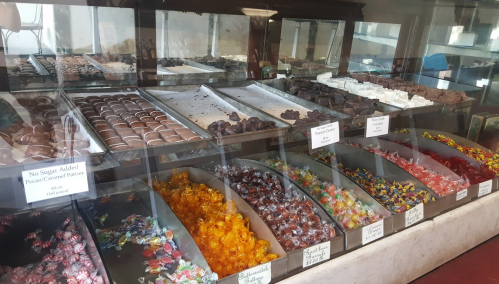 A display case filled with various candies, chocolates, and treats, including colorful gummies and chocolate-covered items.