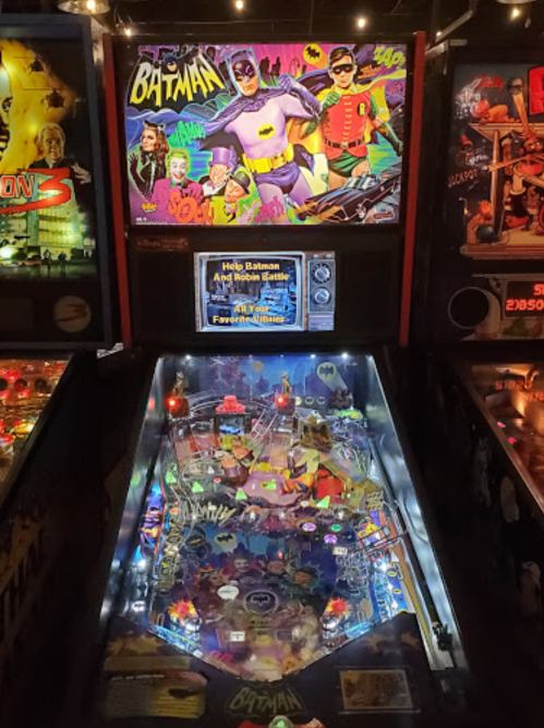 A colorful pinball machine featuring Batman and Robin, with vibrant artwork and illuminated playfield elements.