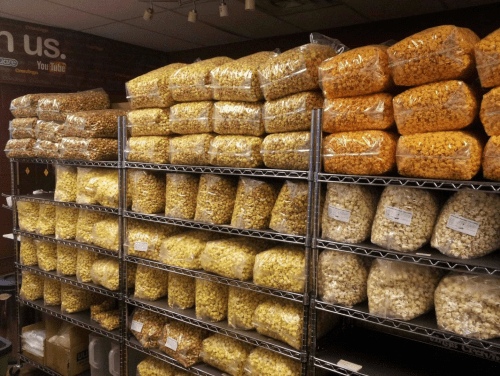 A storage room filled with shelves stacked high with bags of popcorn in various flavors and colors.