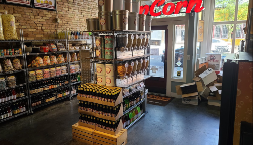 A colorful store interior featuring shelves of snacks, drinks, and popcorn, with a welcoming entrance.