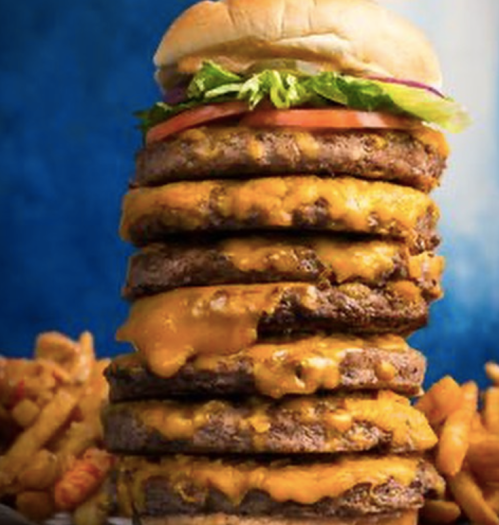 A towering stack of burgers with melted cheese, lettuce, and tomato, set against a blue background.