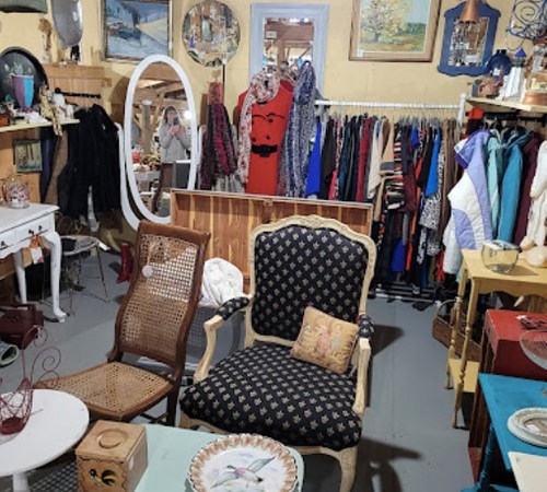 A cozy vintage shop filled with clothing racks, antique furniture, and decorative items.