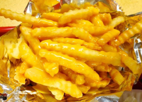 A serving of crinkle-cut fries topped with melted cheese, presented in a foil-lined container.
