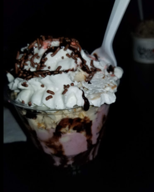 A delicious ice cream sundae topped with whipped cream, chocolate syrup, sprinkles, and a cherry in a clear cup.