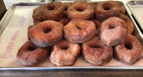 A tray of freshly made cinnamon sugar donuts stacked on parchment paper.