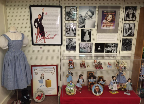 Display featuring memorabilia related to Judy Garland, including photos, dolls, and a costume from "The Wizard of Oz."