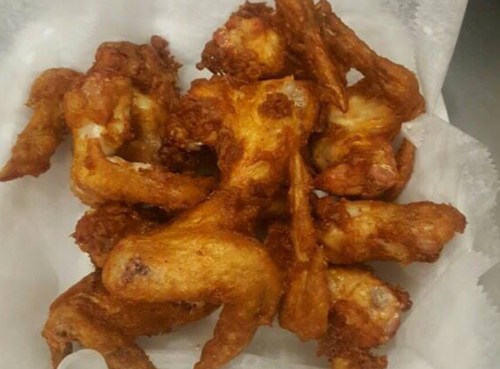 A pile of crispy, golden-brown chicken wings on a white paper liner.