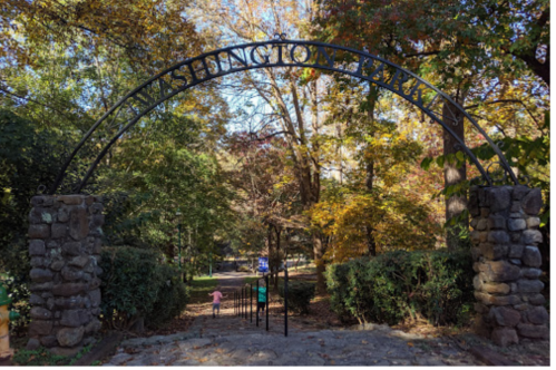 Archway reading "Washington Park" with trees in autumn colors and a child walking down a path.