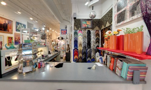 A colorful art and framing shop interior with a counter, display shelves, and vibrant decor.