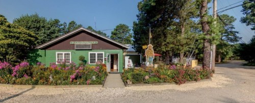 A quaint building surrounded by colorful flowers and greenery, with a sign reading "Glenna's Valley."