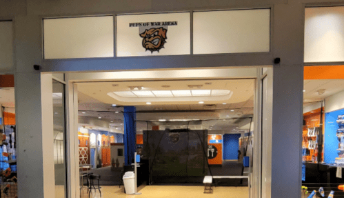 Storefront of "Pups Up War Arena" with a logo above the entrance, showcasing a spacious interior.