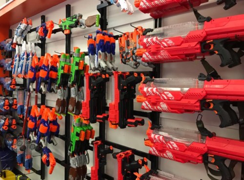 A display of various toy blasters and foam dart guns arranged on a wall.