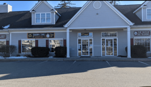 Exterior of a commercial building featuring "Escape Time Adventures" and "Top Notch Dog Training" signs.