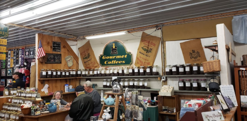 A cozy shop interior featuring jars of gourmet coffee, a counter with customers, and decorative banners.