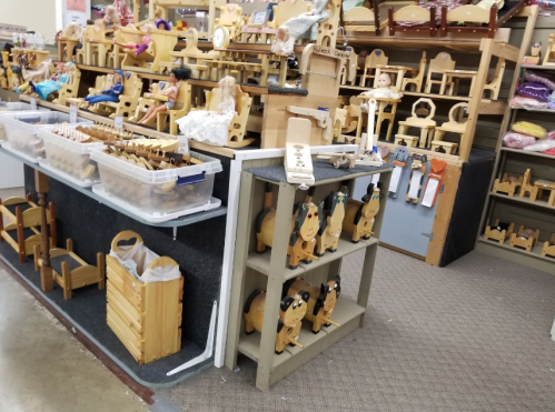 A display of wooden toys and furniture in a store, featuring shelves filled with various handcrafted items.