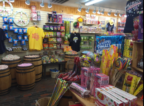 A colorful candy shop filled with various sweets, jars, and barrels, featuring lollipops, gummies, and treats.
