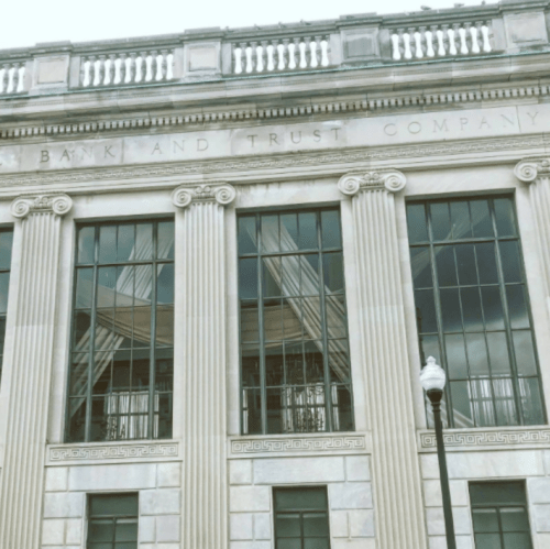 Facade of a classical building with tall columns and large windows, featuring the inscription "Bank and Trust Company."