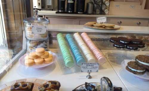 A display of colorful macarons, cookies, and pastries in a bakery window.