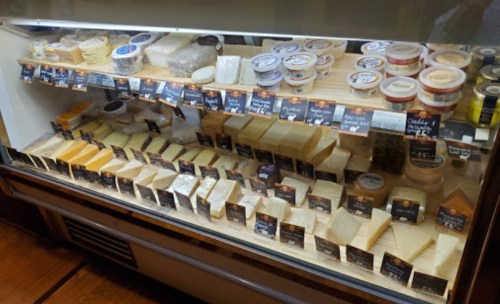 A display case filled with various types of cheese, neatly arranged with labels for each variety.