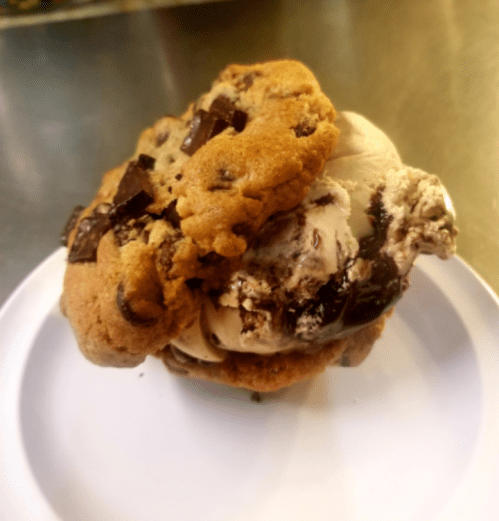 A delicious ice cream sandwich made with two chocolate chip cookies and a scoop of chocolate ice cream in the middle.