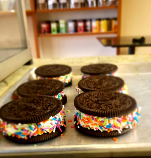 A tray of Oreo cookie sandwiches filled with white cream and colorful sprinkles.