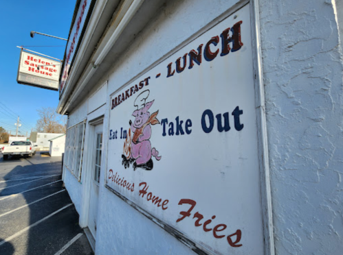 Sign on a restaurant wall advertising breakfast and lunch, featuring a pig graphic and "Delicious Home Fries."