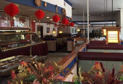 Interior of a restaurant with red lanterns, wooden decor, and green booths, creating a cozy dining atmosphere.